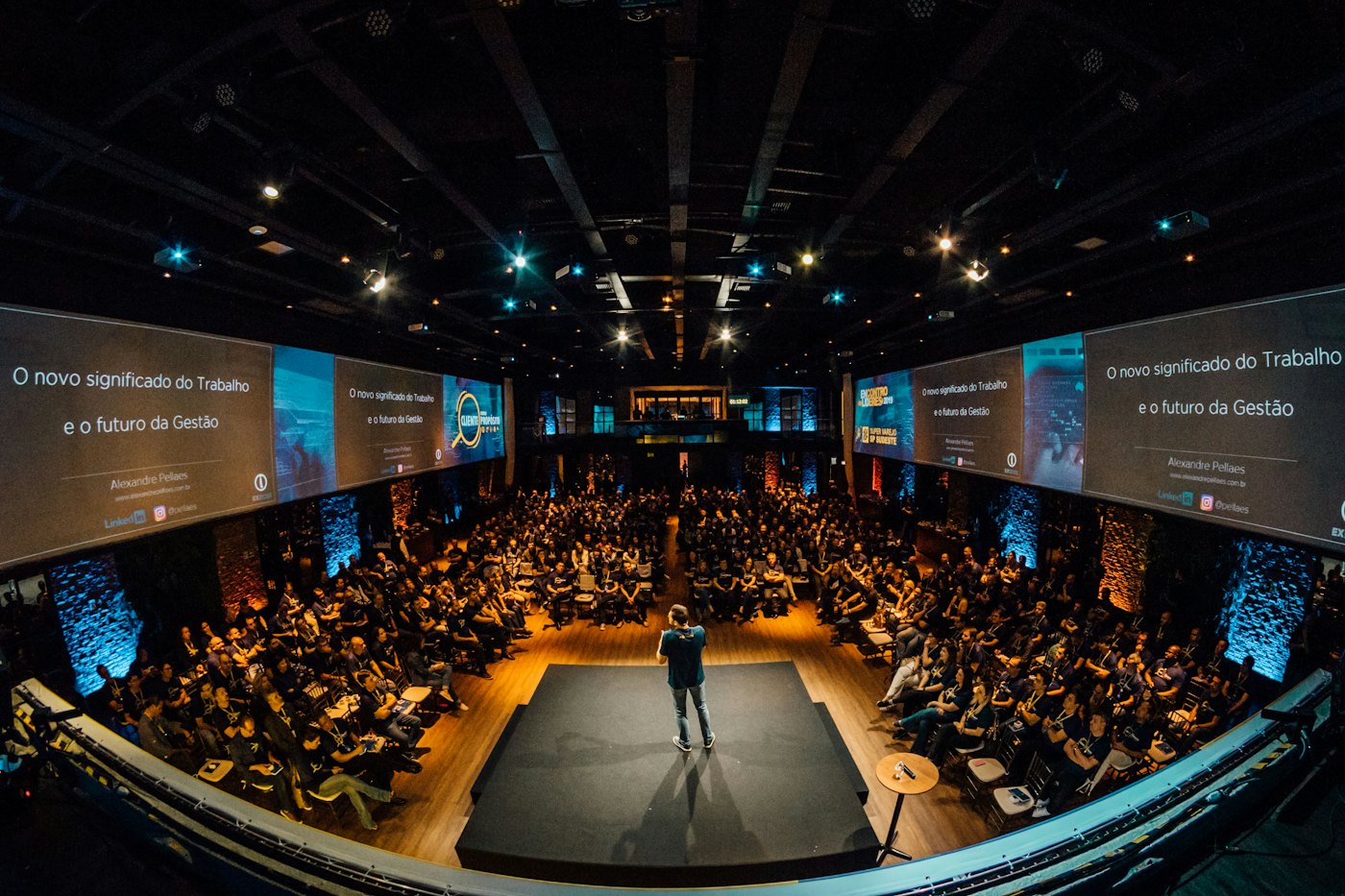 A conference stage with LED screens facing a seated audience