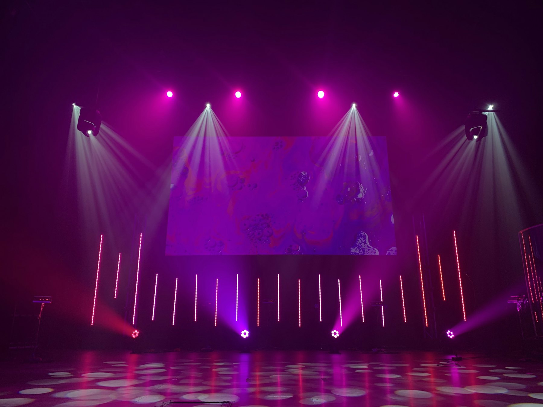 An empty stage with an LED wall and overhead lighting